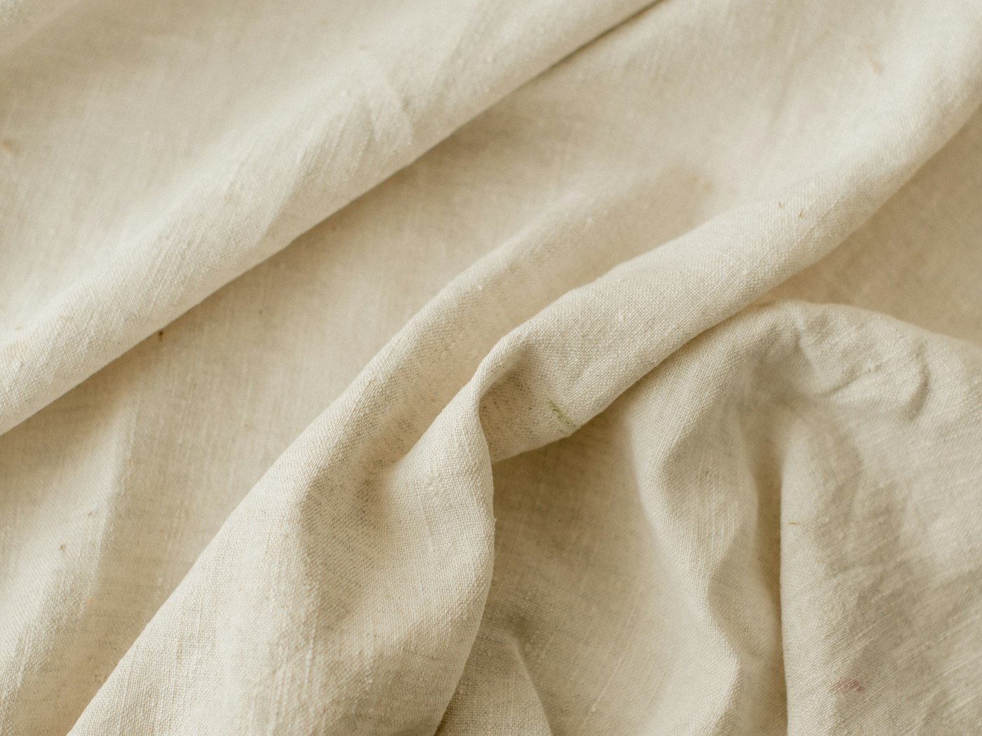 Softly rumpled cream linen fabric in warm light