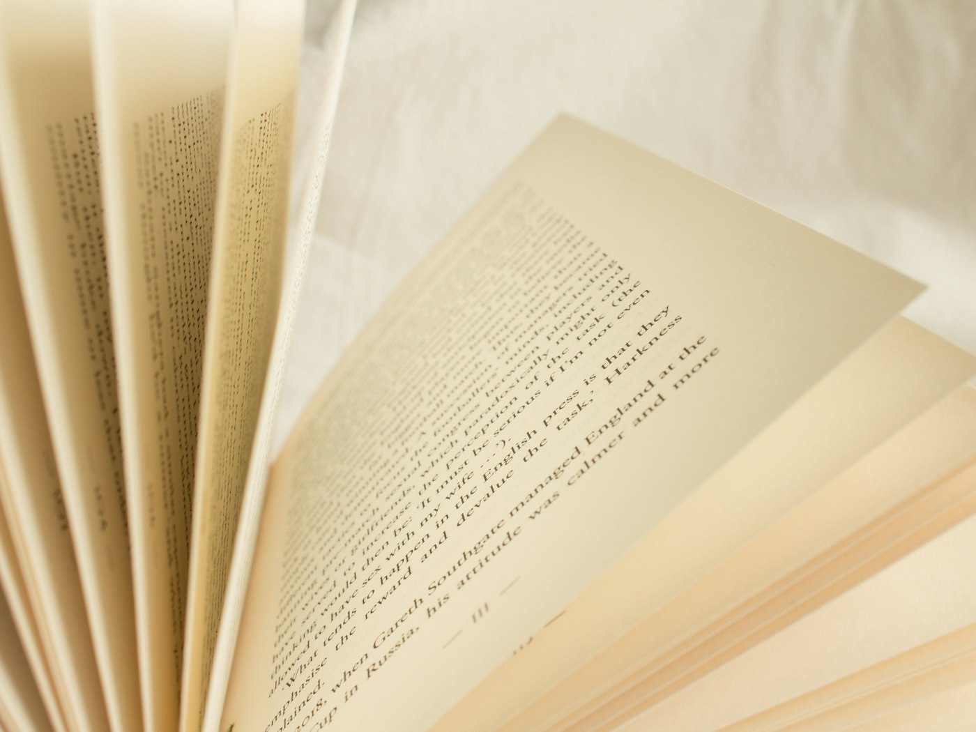 A book fanned open to its pages on soft cream linen